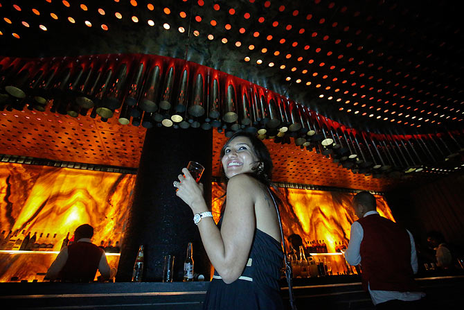 A young girl has a drink while standing next to the bar at the Ren by China Garden nightclub in Mumbai.