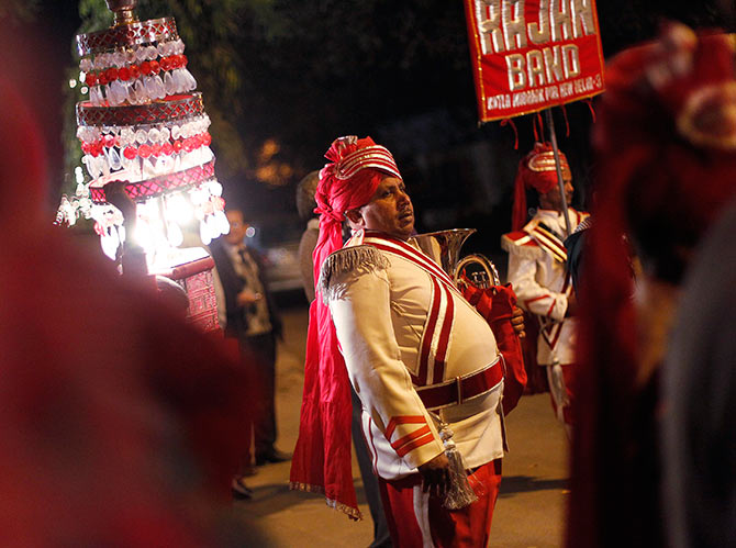 A member of a brass band pauses as his other members perform during a wedding procession in New Delhi.