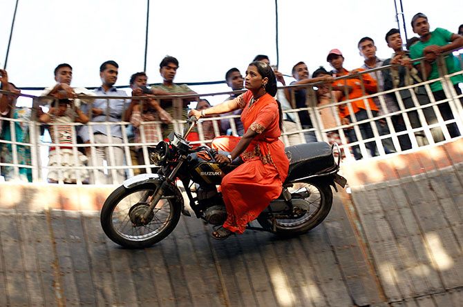 Salma Pathan, 21, from Maharashtra, rides a bike in the 'Well of Death'. Photograph: Adnan Abidi/Reuters