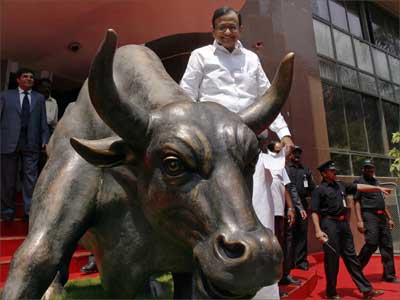 Finance Mnister P Chidambaram poses next to the bronze statue of a bull outside the Bombay Stock Exchange.