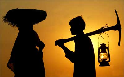Indian labourers are silhouetted against a sunset as they return home after day-long work at a construction site in Chandigarh. | Photograph: REUTERS/Ajay Verma