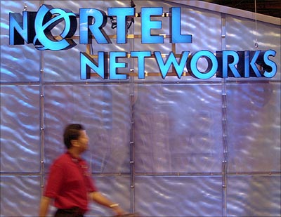 A SuperComm2001 communications convention attendee strolls past the Nortel Networks booth