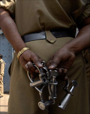 A police officer stands with handcuffs. | Photograph: Krishnendu Halder/Reuters