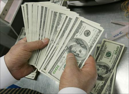 A bank employee counts $100 notes. | Photograph: Jo Yong-Hak/Reuters