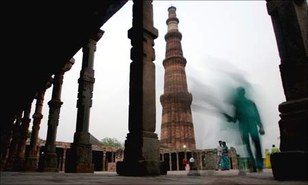 Tourists stand the 72.55 meter-high Qutab Minar in New Delhi. | Photograph: Kamal Kishore/Reuters
