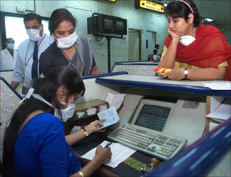 During the avian flu scare in 2003, masked immigration officials checking papers of passengers arriving from Singapore at New Delhi's international airport. | Photograph: Kamal Kishore KK/Reuters