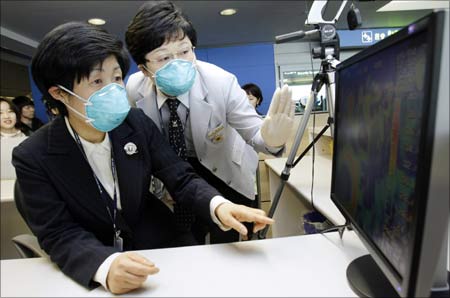 South Korean Minister for Health, Welfare and Family Affairs Jeon Jae-hee (L) and a quarantine officer check a thermal camera that monitors the body temperature of passengers arriving from overseas at Incheon International Airport. | Photograph: Lee Jin-man/Pool/Reuters