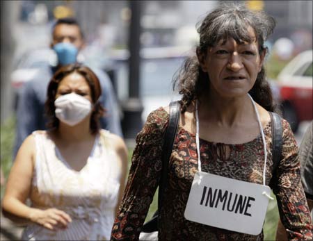 A woman walks with a sign around her neck that reads Immune in Mexico City's main square. | Photograph: Daniel Aguilar/Reuters