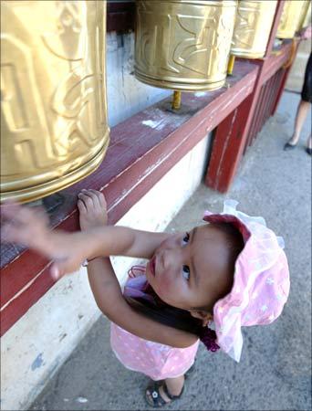 A girl spins prayer wheels at a monastery. | Photograph: Guang Niu/Reuters