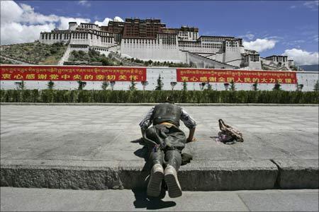 A Tibetan pilgrim prays in front of the Potala Palace in Lhasa. | Photograph: Claro Cortes IV/Reuters