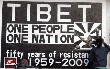 A man creates graffiti on a wall on the eve of the 50th anniversary of the Tibetan uprising in the northern Indian hill town of Mcleodgunj. | Photograph: Fayaz Kabli/Reuters