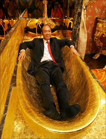 Lam Sai-wing, chairman of Hang Fung Gold Technology Group, poses in a golden bathtub in an exhibition hall decorated with two tonnes of gold next to his jewellery shop in Hong Kong. | Photograph:  Bobby Yip/Reuters