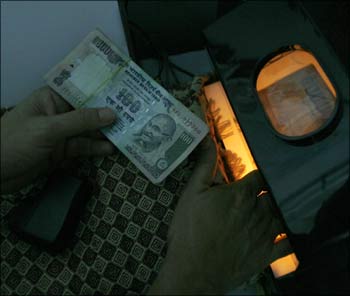 A teller checking a currency note.