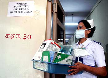A nurse carries masks and medicine outside the influenza A (H1N1) ward in Mumbai.