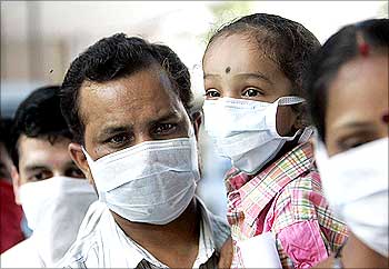 People wearing masks wait in a queue for a H1N1 flu screening at a hospital in New Delhi.