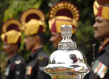 An Indian soldier is reflected on an official emblem of the government of India during Vijay Diwas.