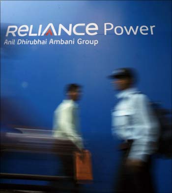 People walk past a sign of Reliance Power outside the Bombay Stock Exchange building in Mumbai in February, 2008.