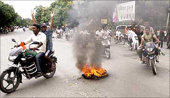 Protestors shout slogans as they drive past a burning tyre at a rally during a strike in Siliguri.