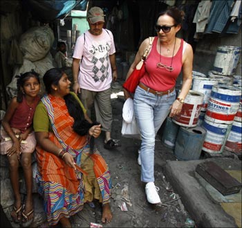 A tourist walks through Dharavi, one of Asia's largest slums, during a guided tour as local residents look on in Mumbai.