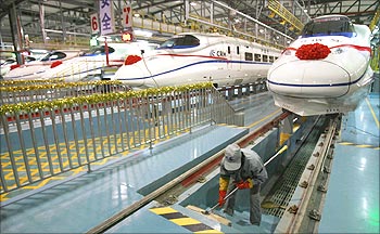 A labourer cleans the stairs beside a China Railway High-speed (CRH) train.