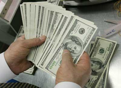 A bank employee counts one hundred dollar notes.