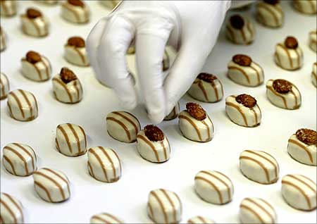 An employee places almonds on pralines at a Swiss chocolate plant in Zurich.