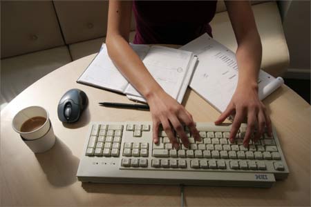 A woman working at her desk typing on a computer.