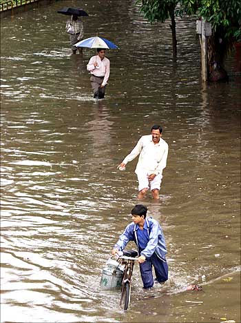 Office workers make their way through a flooded street in Mumbai.