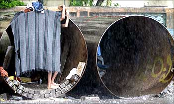 A boy uses a cloth to block rain water from entering his make-shift home in a waterpipe in Mumbai.