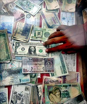 A currency dealer displays various currencies at his roadside money changer stall.