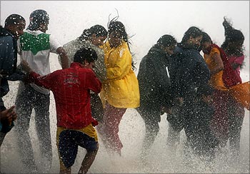 People get drenched by a large wave during high tide at Mumbai's seafront.