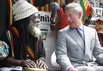 Britain's Prince Charles laughs with a Jamaican drum player during a tour the Bob Marley Museum in Kingston.