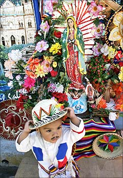 A Salvadoran child poses for photographs beside an image of the virgin of Guadalupe outside the Basilica of Guadalupe in San Salvador.