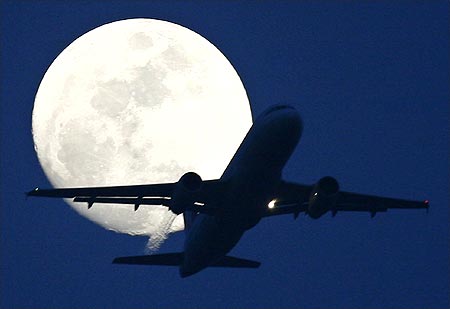 A passenger aircraft is silhouetted against the rising moon in New Delhi.