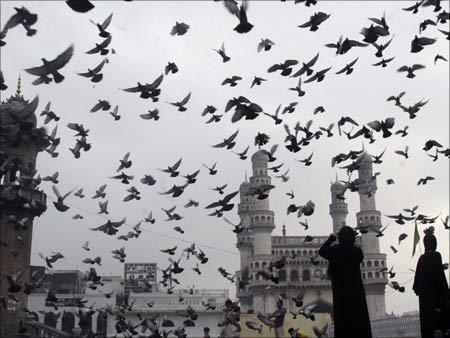 Pigeons fly against the backdrop of the historic Charminar monument in Hyderabad.