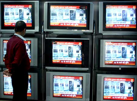 An electronics shop employee in Jammu watches visuals at a shop in Jammu.