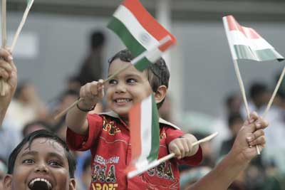 A cheerful boy waves Indian flags.