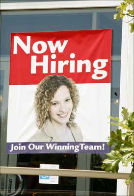 A 'Now Hiring' sign is displayed in the window of a shop. | Photograph: Rick Wilking