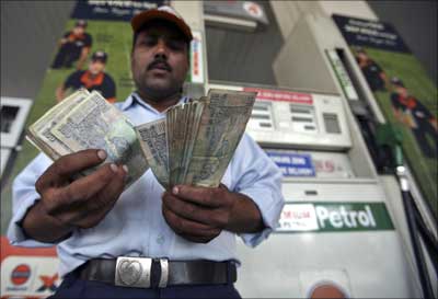 A worker at a gas station counts currency notes.