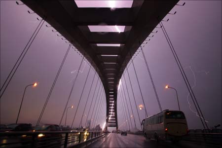 A lightning bolt illuminates the sky above Lupu Bridge during an electrical storm in Shanghai.