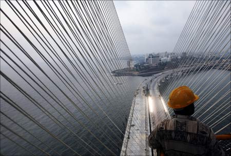 A worker stands on top of a tower at the construction site of the Bandra-Worli sea link in Mumbai.