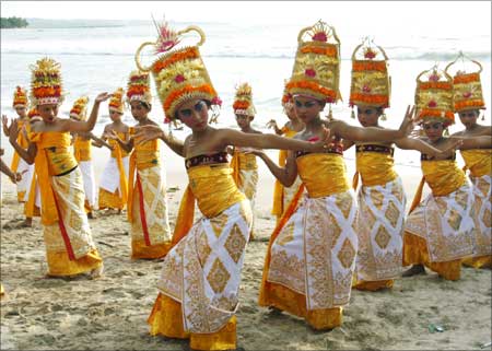 Balinese girls in traditional dress dance on Kuta beach during the Melasti ceremony in Kuta, Bali.