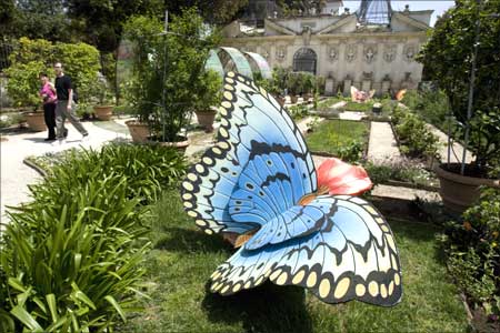 A couple walks past a wooden butterfly in the gardens of Galleria Borghese in Rome.