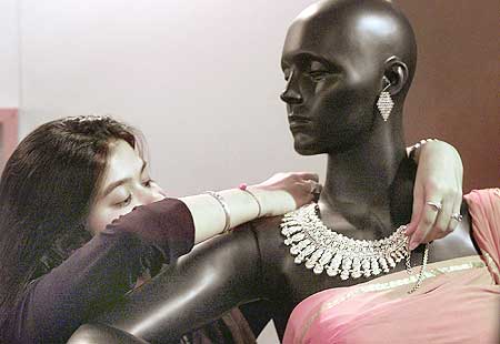 An attendant decorates a mannequin with silver jewellery.
