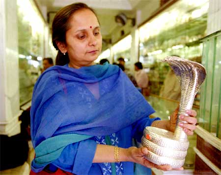 A woman looks at a cobra made of silver.