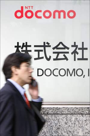 A man walks past a signboard of Japan's biggest mobile phone operator NTT Docomo Inc. in Tokyo.