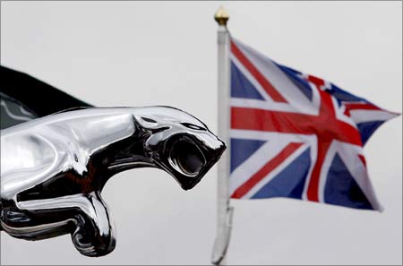 A Union flag flies behind a Jaguar car emblem outside a dealership in Manchester, England.