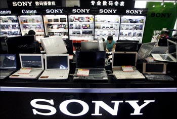 Sales staff talk with customers behind a row of Sony computers for sale at a computer market in Beijing.-Reuters