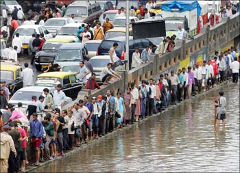 People walk home as traffic after came to a standstill following heavy rains on July 26, 2005, in Mumbai.