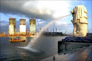 A tourist boat travels near the Merlion statue overlooking the Marina Bay Sands Casino construction.